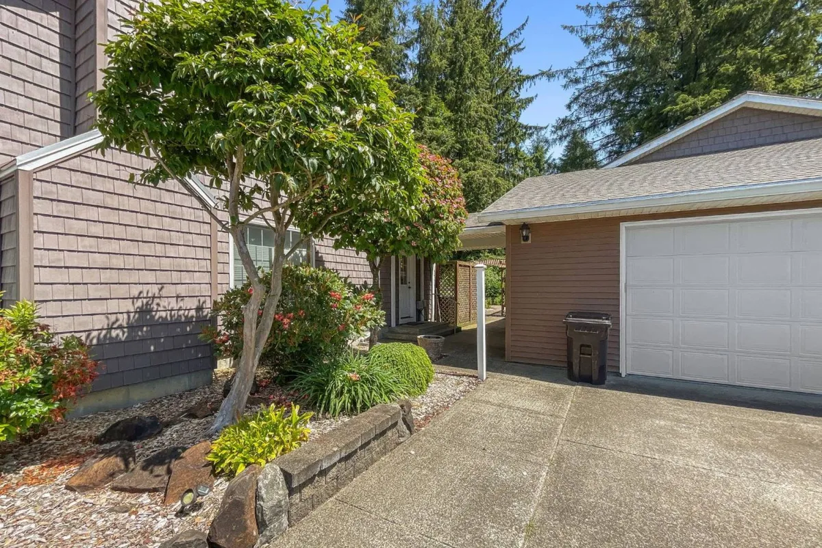 This exterior view includes a manicured garden, a prominent tree, the front door, and a garage. The scene radiates warmth and invitation, suggesting a welcoming arrival and generous outdoor space for gatherings and pet play.