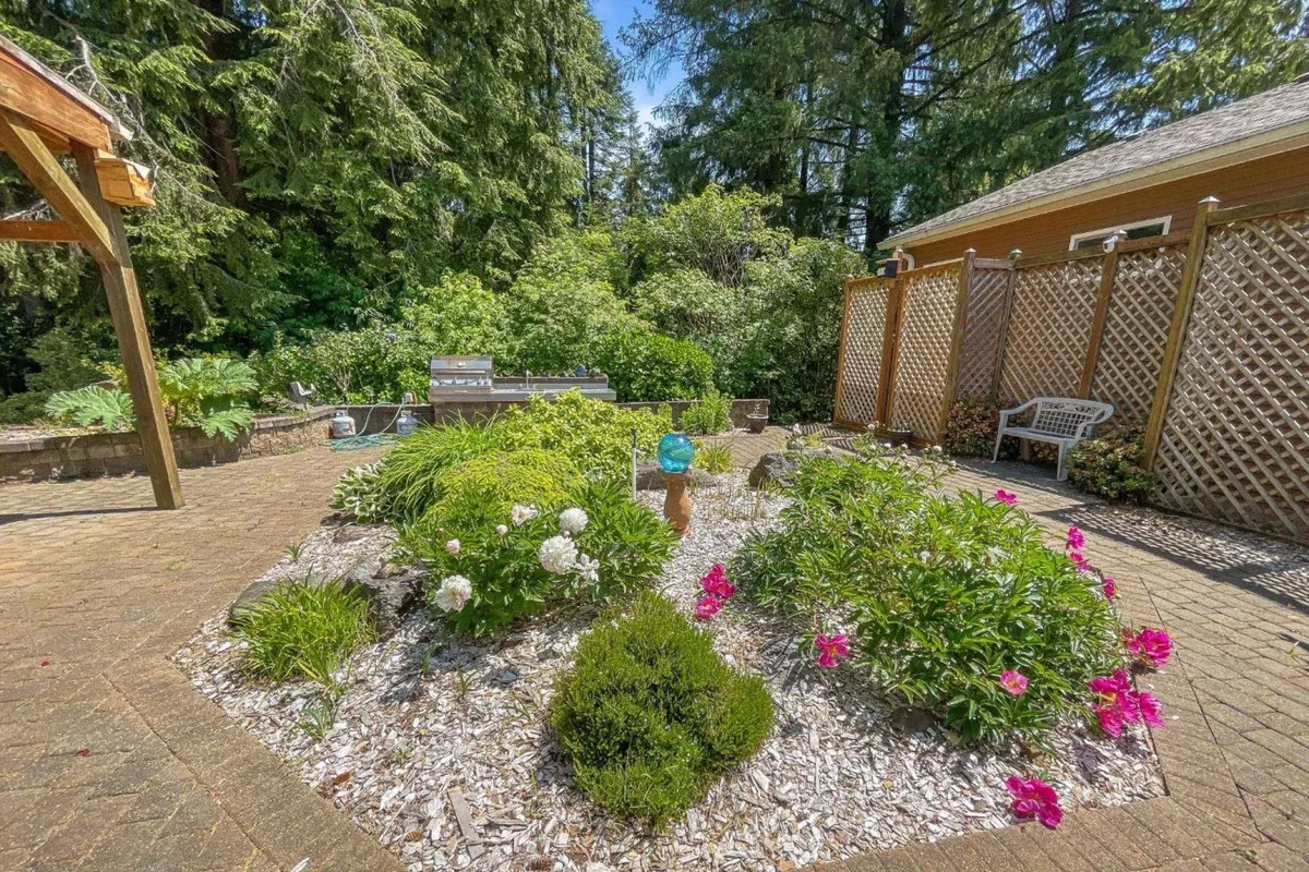 A tranquil exterior shot showing a flower bed adorned with a decorative garden ornament and a cozy patio seating area. The landscaping is vibrant and peaceful, offering plenty of space for pets to play or owners to unwind.